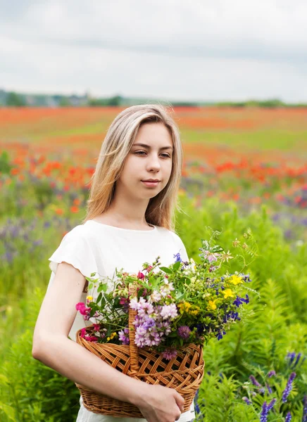 Vacker blond flicka med korg med blommor — Stockfoto