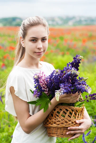 Flicka med korg av Lupin blommor — Stockfoto