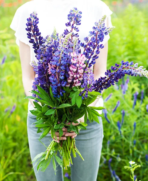 Frau hält einen Strauß Lupinen in der Hand — Stockfoto