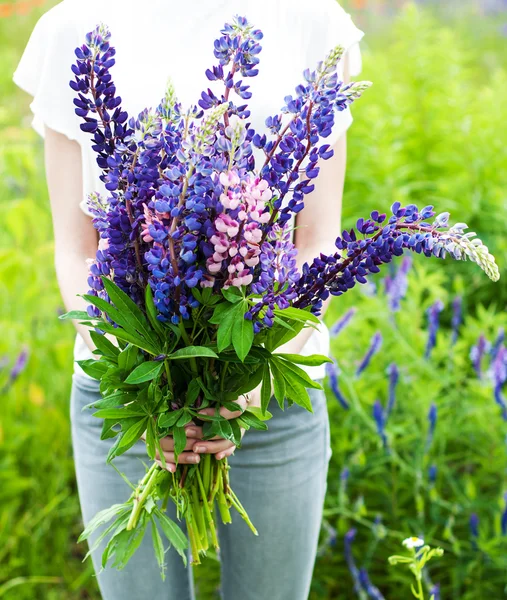 Frau hält einen Strauß Lupinen in der Hand — Stockfoto