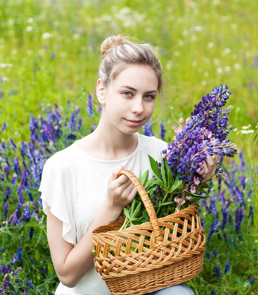 Flicka med korg av Lupin blommor — Stockfoto