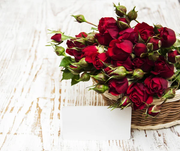 Rosas vermelhas em cesta e cartão de saudação — Fotografia de Stock