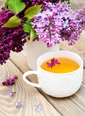 Fincan çay ve eflatun çiçekler