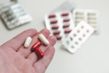 Arka planda ilaç bulunan kırmızı ve beyaz kapsüller. Farklı kabarcıklar, haplar, seçici odaklanma.