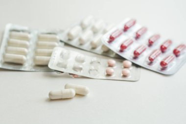 Kabarcıklarda ilaç ve vitamin içeren kapsüller ve beyaz bir yüzey üzerinde seçici bir odak noktası.