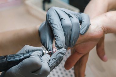 Manikürcü tırnak derisini donanım metoduyla işliyor, yakın plan.