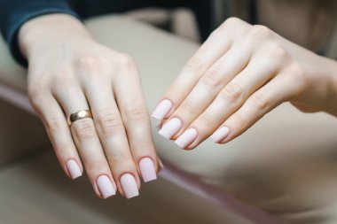 Tırnaklarının jel kaplamasını düzelttikten sonra çivileri olan ve renkli cila sürmeden önce güzel bakımlı eller.