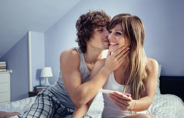 Young couple with pregnancy test in bedroom — Stock Photo, Image