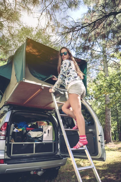Женщина, стоящая в лестнице и открывающая палатку над машиной — стоковое фото
