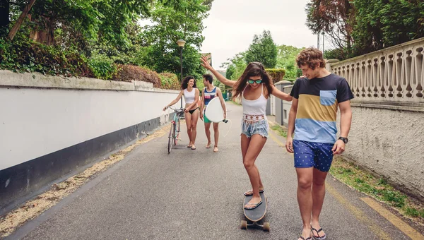 Happy young woman riding on skate with her friends — Stock Photo, Image
