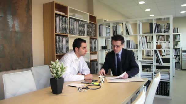 Insurance agent showing health documents to doctor — Stock Video