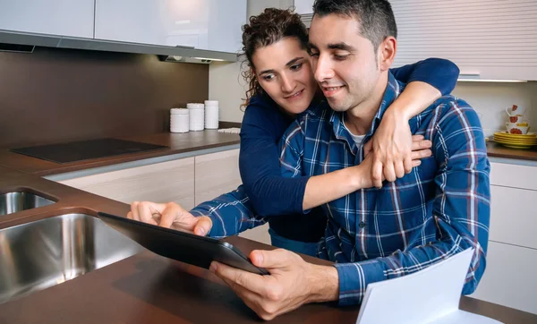 Casal alegre usando tablet digital em casa de cozinha — Fotografia de Stock