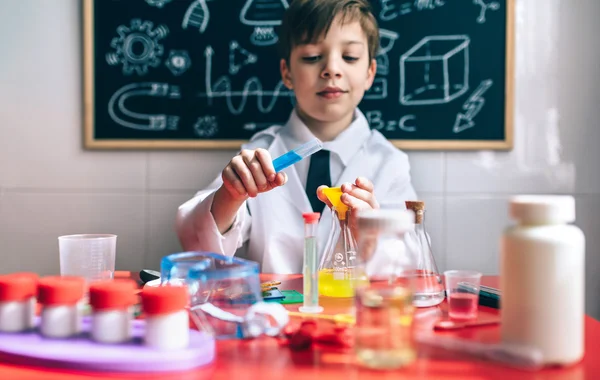 Niño serio jugando con líquidos químicos — Foto de Stock