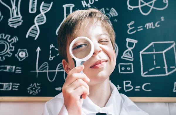 Little boy looking at camera through magnifying glass — Stock Photo, Image