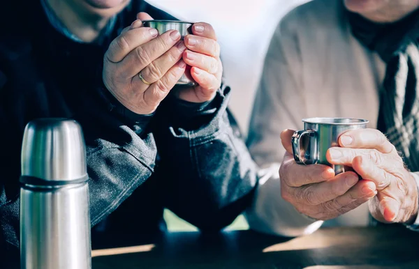 Sénior casal mãos segurando copos com café quente — Fotografia de Stock