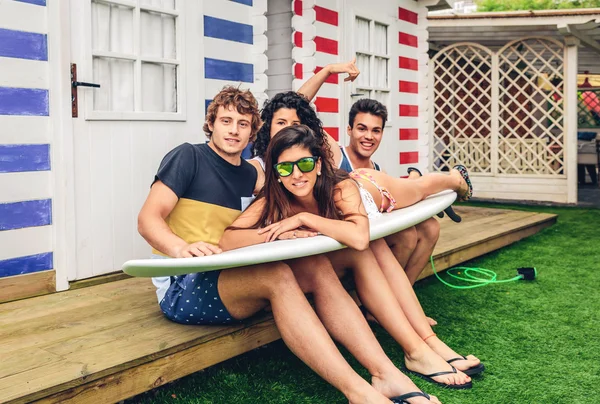 Young friends holding woman on top of surfboard — Stock Photo, Image