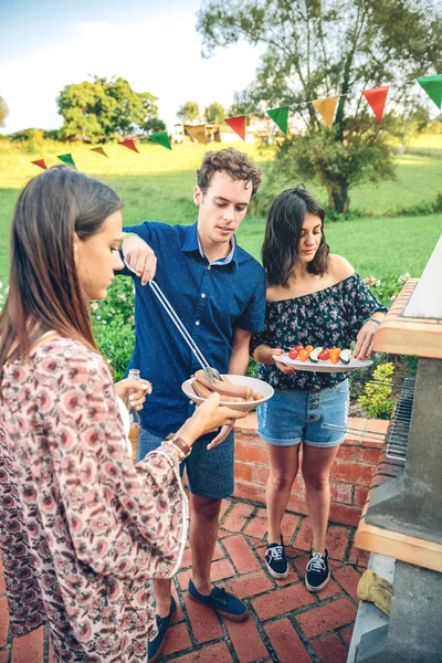 Gruppo di amici cucina in un barbecue estivo — Foto Stock