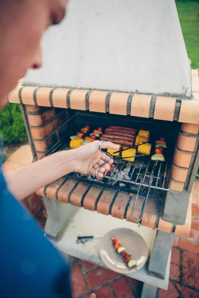 Jeune homme méconnaissable cuisiner un repas dans un barbecue — Photo