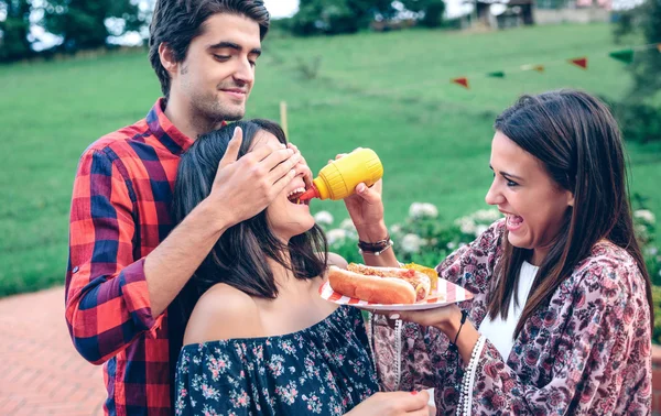 Uomo in possesso di hot dog in barbecue con gli amici — Foto Stock