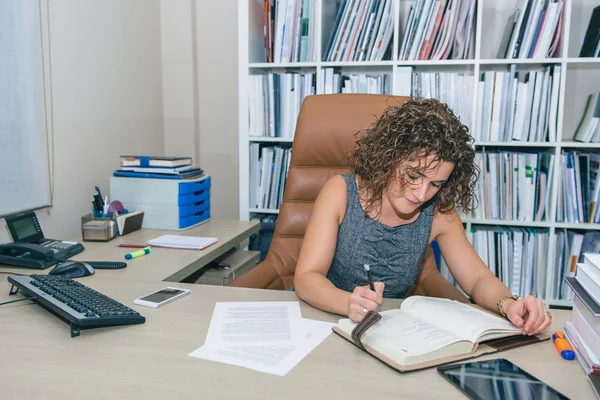 Empresaria escribiendo en cuaderno sentada en la oficina —  Fotos de Stock