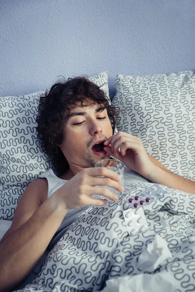 Retrato del hombre enfermo tomando medicamentos acostado en la cama —  Fotos de Stock