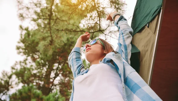 Mulher com óculos de sol levantando os braços sobre o fundo da natureza — Fotografia de Stock