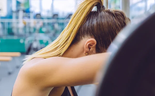 Unavená žena odpočívá po zvednutí činka na svalové školení — Stock fotografie