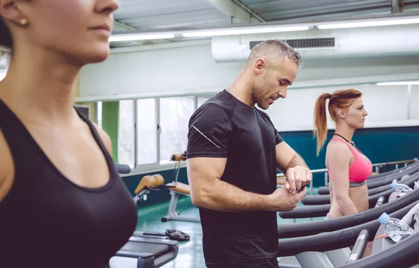 Mann kontrolliert Herzfrequenz auf Uhr beim Laufband-Training — Stockfoto