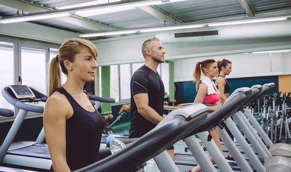 Osoby trenujące na bieżniach w centrum fitness — Zdjęcie stockowe