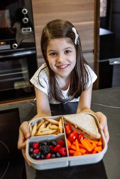 Gelukkig meisje tonen lunch doos gevuld met gezond voedsel — Stockfoto