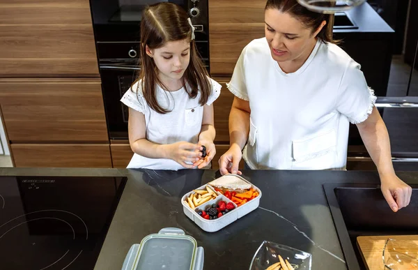 Anne kızının beslenme çantasına yemek koyuşunu izliyor. — Stok fotoğraf