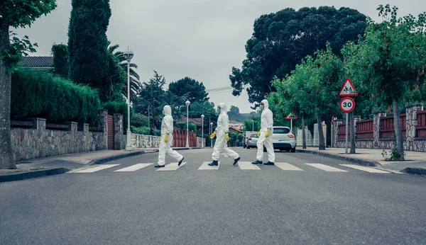 Gente con trajes de protección bacteriológica caminando por una calle vacía — Foto de Stock