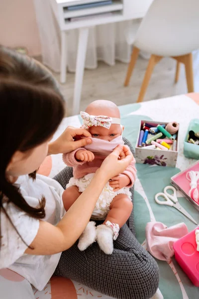 Mädchen versucht auf ihrer Puppe eine Maske, die sie näht — Stockfoto