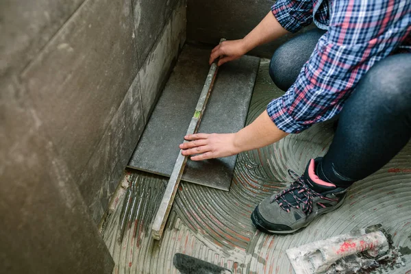 Unerkennbare Maurerin Überprüft Den Boden Mit Einer Ebene Einen Fliesenboden — Stockfoto