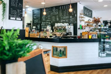 İçinde kahve makinesi olan boş bir kafe ve menüsü olan karatahta.