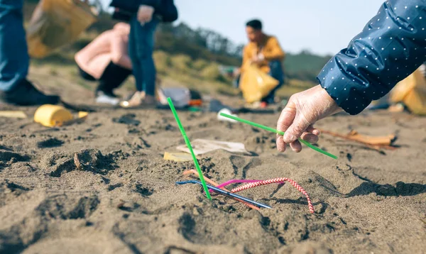 Woman picking up straws on the beach — Stock Photo, Image