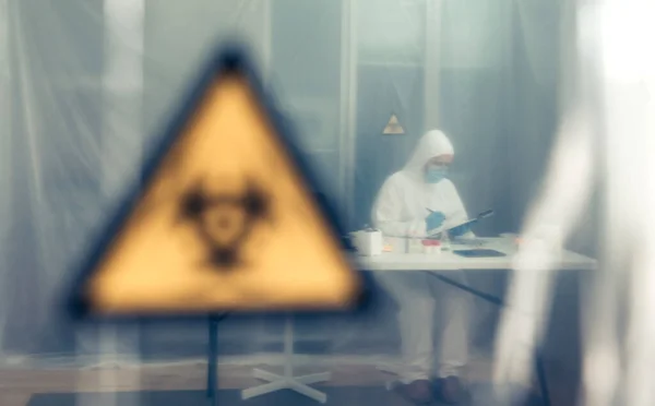 Wetenschapper onderzoekt in het laboratorium achter een beschermend gordijn — Stockfoto