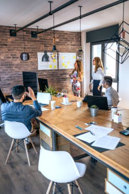 Kadın yönetici, çalışanlarına bir iş toplantısında açıklama yapıyor.