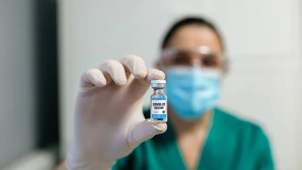 Vrouwelijke laboratoriumtechnicus die flacon met coronavirusvaccin toont — Stockfoto
