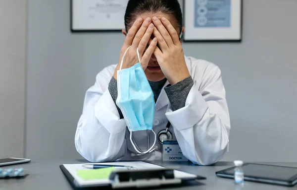 Médica com fadiga pandêmica cobrindo o rosto — Fotografia de Stock