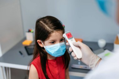 Ateşi olan ve doktoru tarafından ölçülen bir kız.