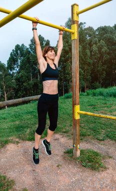 Kadın sporcu barfiks egzersizi yapıyor.