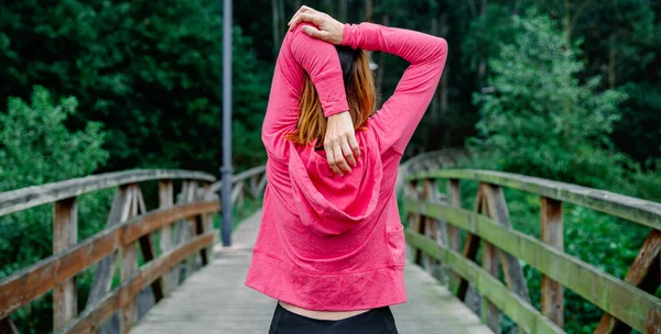 Nierozpoznana sportowiec robi rozciąganie ramion na zewnątrz — Zdjęcie stockowe