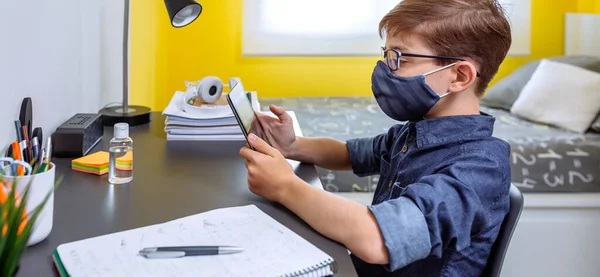 Boy with face mask doing homework with a tablet — Stock Photo, Image
