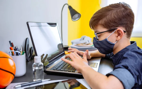 Teenager mit Gesichtsmaske macht Hausaufgaben mit Laptop — Stockfoto