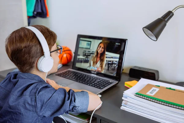 Jongen met hoofdtelefoon die thuis les krijgt met laptop uit zijn slaapkamer — Stockfoto