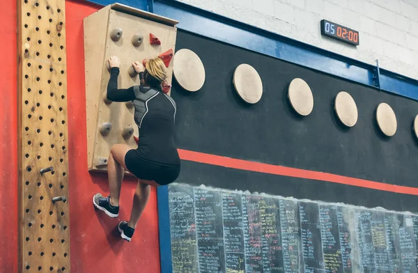 Mulher pendurada na parede de escalada — Fotografia de Stock