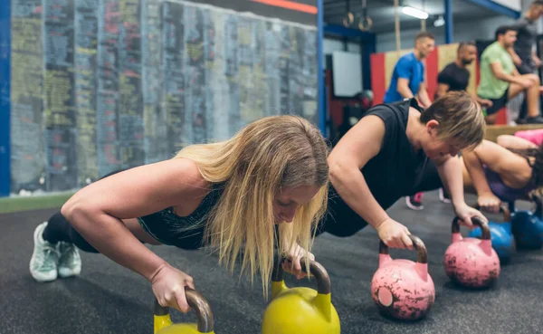 Sportvrouwen die push-ups doen met kettlebells — Stockfoto