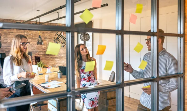 Gente de negocios en una reunión de trabajo colocando notas adhesivas en la pared — Foto de Stock