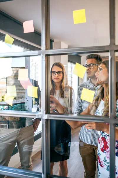 Gente de negocios en una reunión de trabajo colocando notas adhesivas en la pared — Foto de Stock